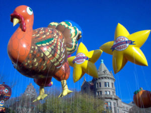 giant 20ft tall turkey helium parade balloon in air with two yellow star balloons